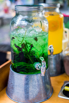 Glass jars with cold lemonade/Glass jars with cold green and orange lemonade on the counter a street vendor