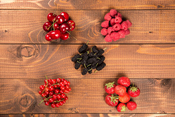 Fototapeta na wymiar Collection of cherries, strawberries, mulberries, red currants, raspberries on wood background