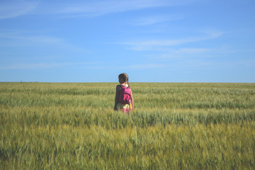 Little girl with backpack walking in a field