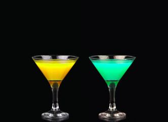 Yellow and green cocktail in martini glass isolated on black background