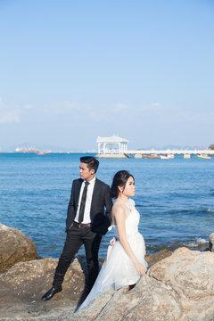 Couple standing on the rocks by the sea.