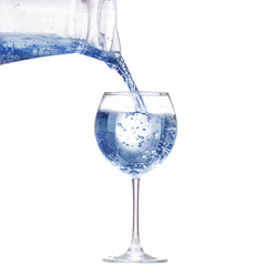Pouring water from glass pitcher on white background