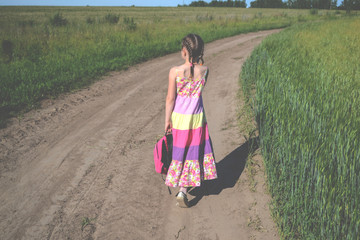 Little girl in dress walking along the road
