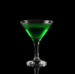 Green alcoholic cocktail in a glass on black