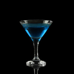 blue alcoholic cocktail in a glass on black