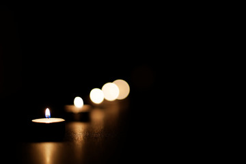 Candles arranged diagonally and burning in the darkness.