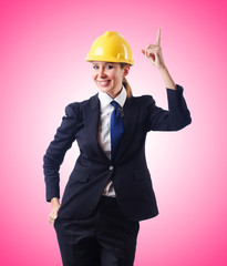 Young businesswoman with hard hat against gradient 