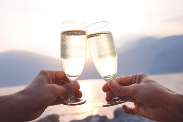 Lovers toast with wite wine at sunset