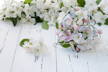 Spring apple tree blossoms and vintage cage heart on white old wooden background. Wedding or valentine concept