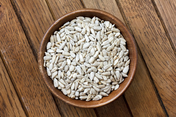 Shelled sunflower seeds in wood bowl isolated from above on rust