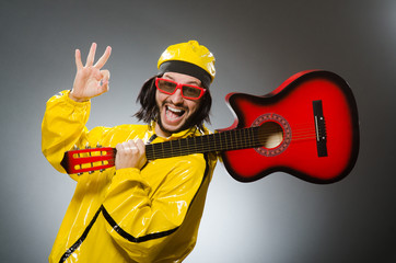 Funny man wearing yellow suit and playing guitar