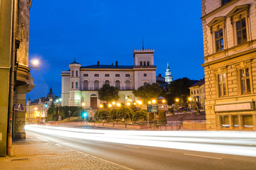 Fototapeta premium Night traffic on main Zamkowa street in front of Sulkowski Castle
