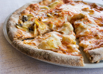 pizza with ham mushrooms and artichokes in the plat.
