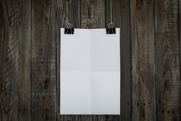 Black clip and White paper hang on wood background