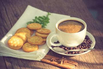 Cup of coffee on a wooden board and biscuits vintage color