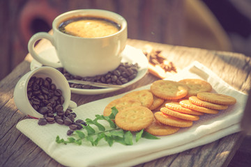 Cup of coffee on a wooden board and biscuits vintage color