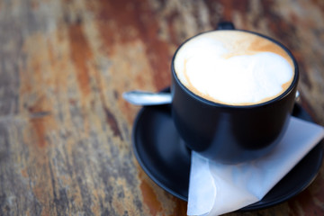 Coffee in black cup on wood table