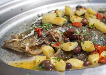 Baked flounder fish with potatoes, olives and tomates