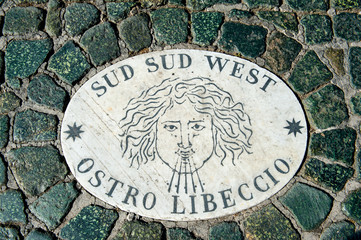 Old wind marker on cobblestone pavement