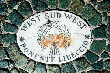 Old wind marker on cobblestone pavement