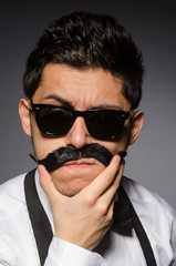 Young man with false moustache isolated on gray