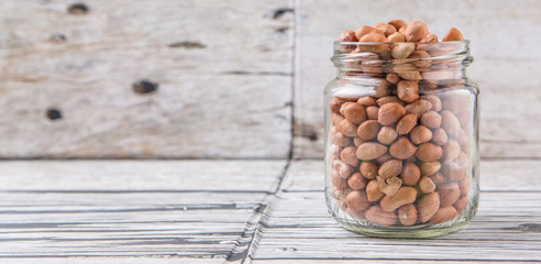 Ground nut or peanuts in a mason jar over weathered wooden background