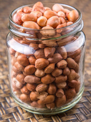 Ground nut or peanuts in a mason jar over wicker background