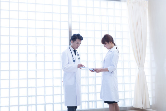 病院内で書類を見ながら話し合う男性医師と」女性医師