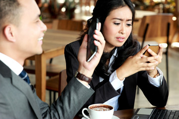 two business people look busy with their own mobilephone