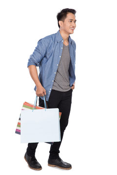 Young asian man walking and holding shopping bags, full body