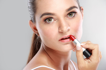 beautiful young woman applying lipstick