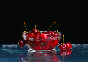 Glass bowl with cherry berries on black