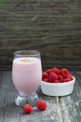 berry milkshake and fresh raspberries on a wooden background