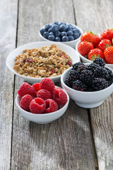 garden berries and muesli on wooden background, vertical