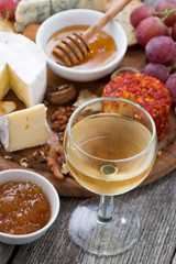 glass of cold white wine and snacks on a wooden table, top view