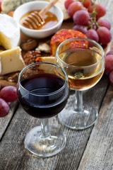 glass of white and red wines, appetizers on a wooden table