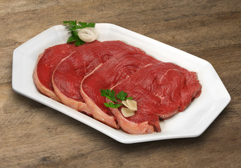 Raw meat selection on wooden cutting board with knife