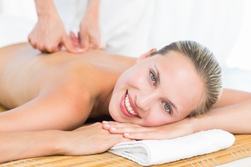 Obraz na płótnie Canvas Pretty blonde enjoying a massage smiling at camera
