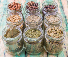 Herbs and spices on in mason jar over weathered wooden background