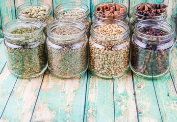 Herbs and spices on in mason jar over weathered wooden background