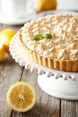 Lemon meringue pie on cake stand on grey wooden background