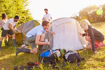 Group Of Young Friends Pitching Tents On Camping Holiday