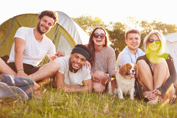 Group Of Friends Relaxing Outside Tents On Camping Holiday