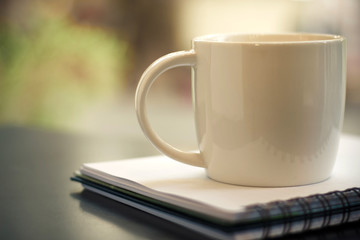 Close up white cup on book on black table selective focus - vintage filter