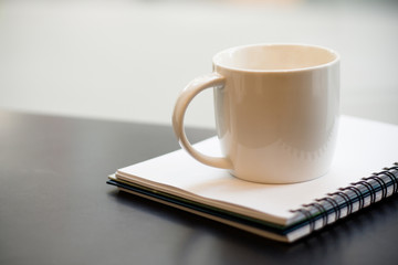 White cup on book on black table selective focus - vintage filter