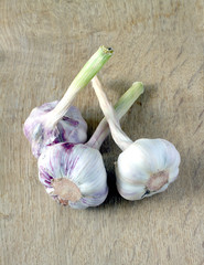 Three heads of ripe garlic lie on a wooden background. Photo closeup