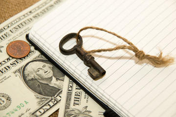 Opened notebook, key and money on the old tissue