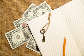 Opened notebook, pencil, key and money on the old tissue