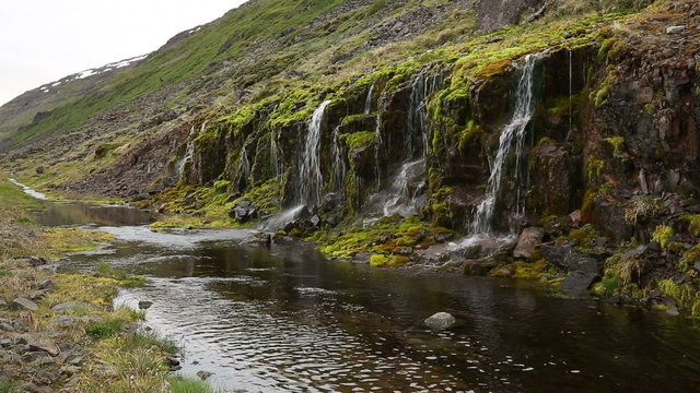 Stone wall with green moss and water trickling down everywhere.