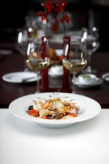 Nice meal served on the table with glasses of white wine in the background, shallow depth of field